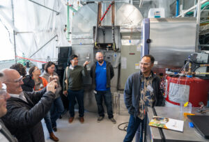 A group of people stand in a lab taking a picture of a water heater
