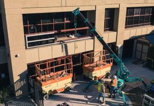 Construction workers install windows on a building.