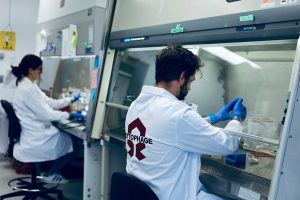 Two people in white coats work in a lab setting.