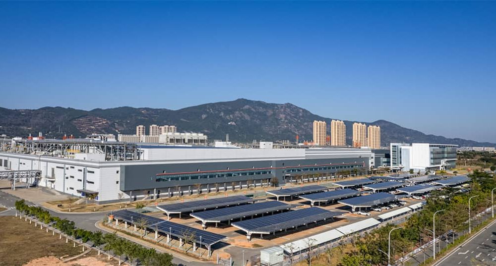 Commercial buildings with solar panels sit in front of mountain foothills.