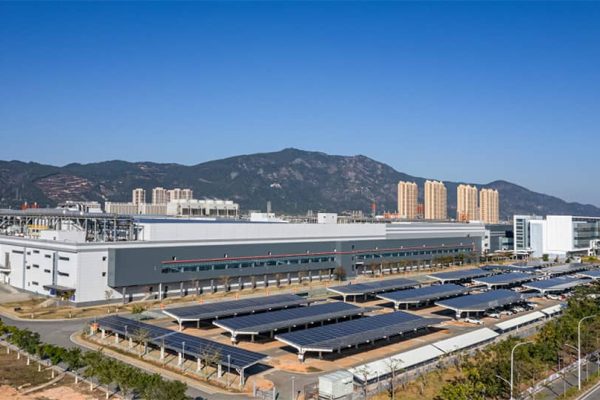 Commercial buildings with solar panels sit in front of mountain foothills.