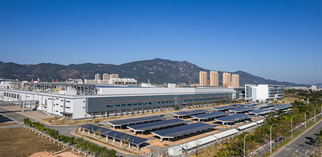 Commercial buildings with solar panels sit in front of mountain foothills.