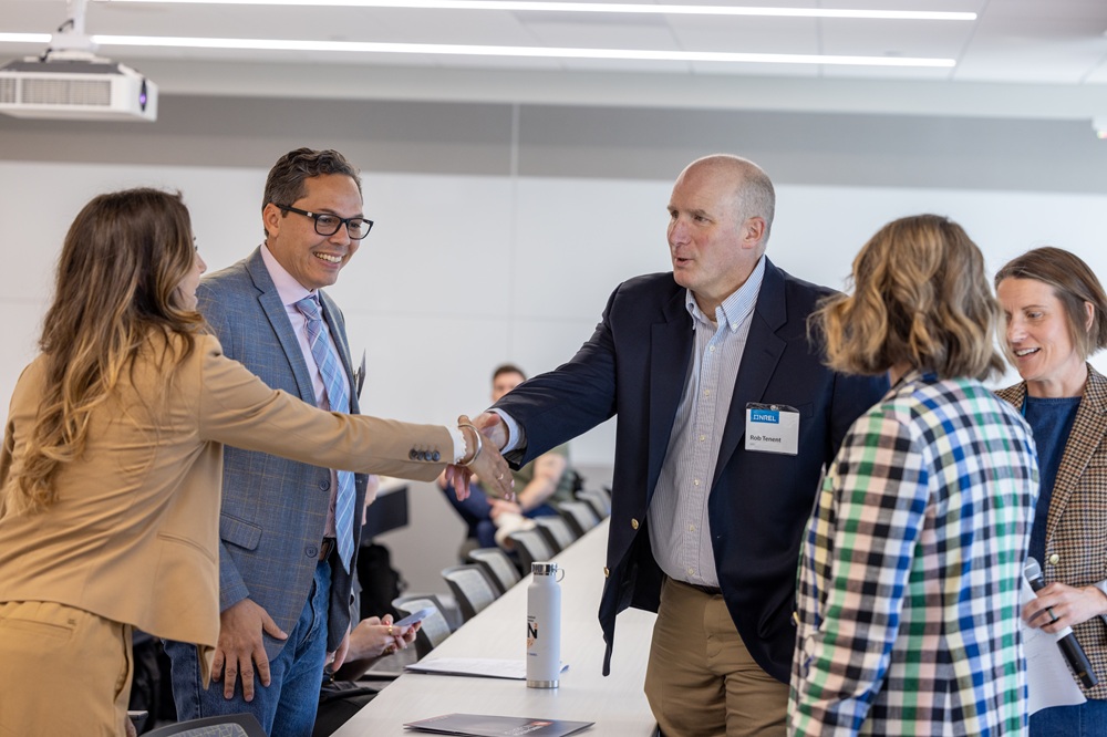 Two people in business casual dress shake hands.
