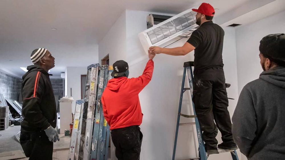 Four men install an HVAC unit in a home.