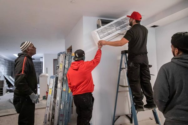 Four men install an HVAC unit in a home.