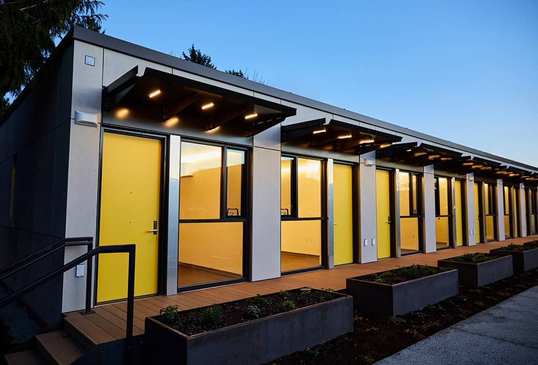 A row of modular homes lit up at dusk.