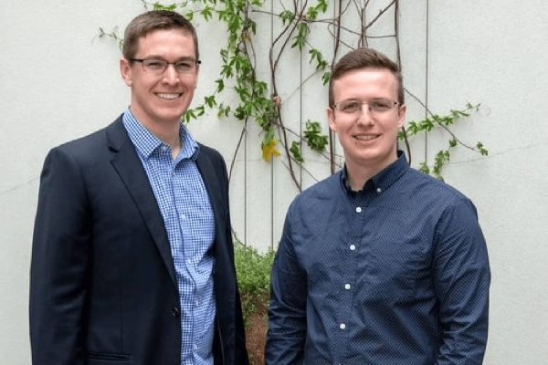 Two men smile for photo.