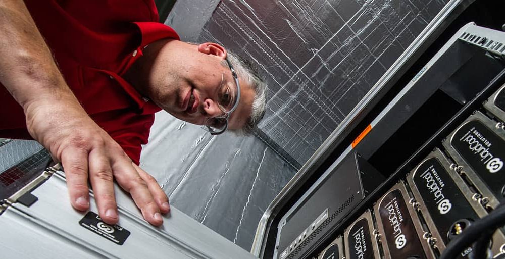 A man stands over a machine and adds a blade to the rack.