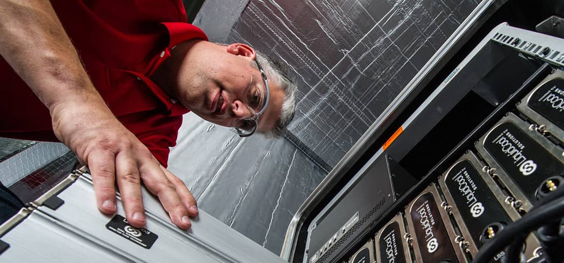 A man stands over a machine and adds a blade to the rack.