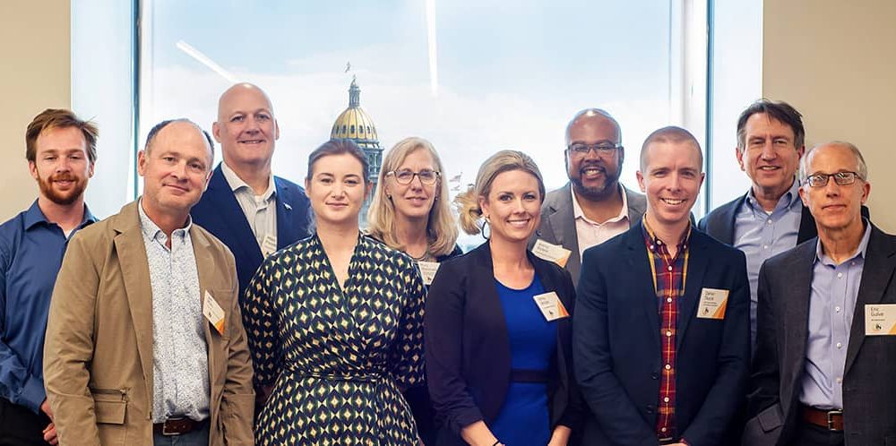 A group of 10 people pose and smile for the camera.