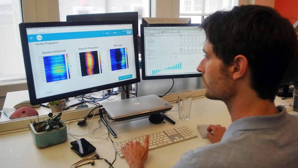 A man viewing dual monitors displaying colorful graphs and data analysis.