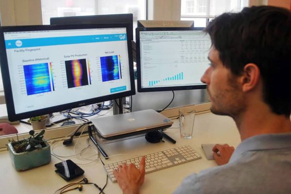 A man viewing dual monitors displaying colorful graphs and data analysis.