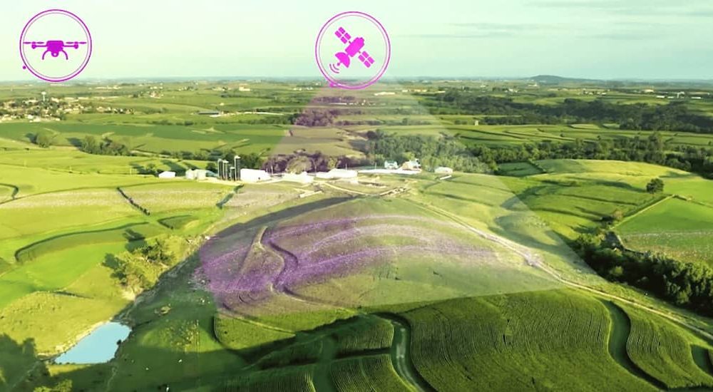 Aerial view of farmland with icons of a drone and satellite.