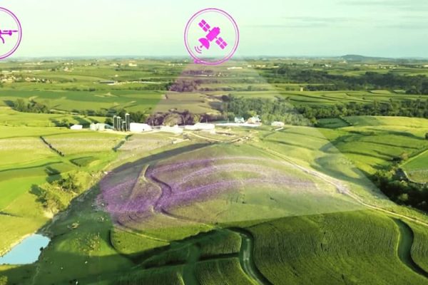 Aerial view of farmland with icons of a drone and satellite.