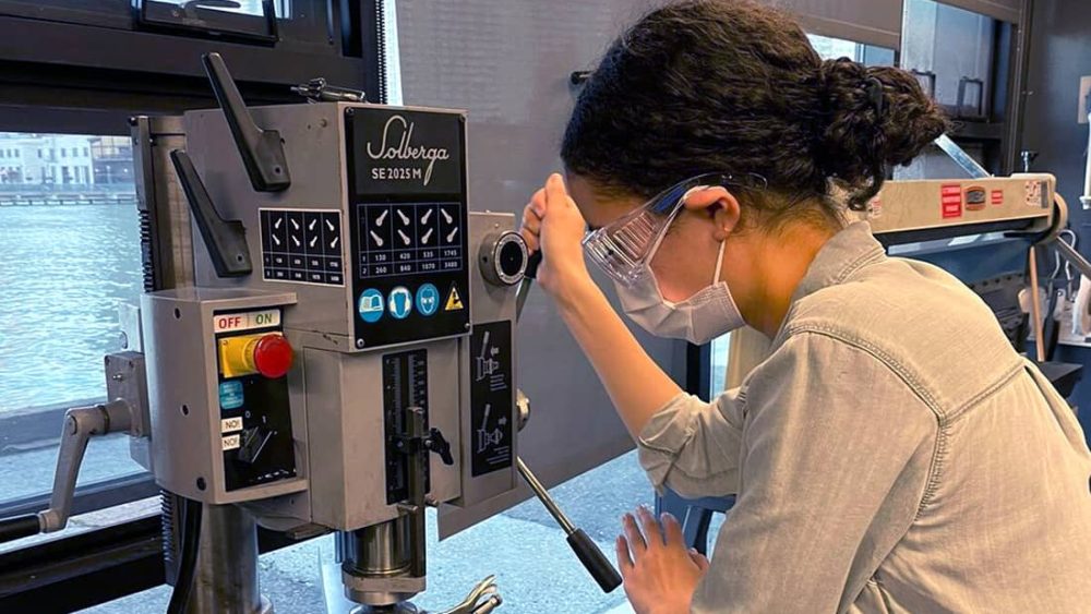 Woman wears safety goggles and operates machinery