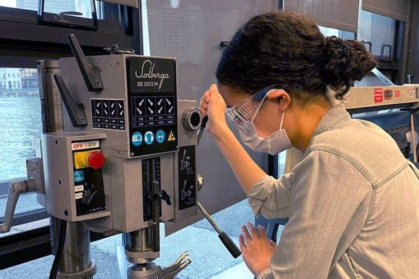 Woman wears safety goggles and operates machinery