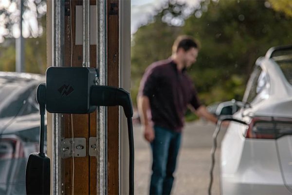 A man charges his car in front of NeoCharge technology.