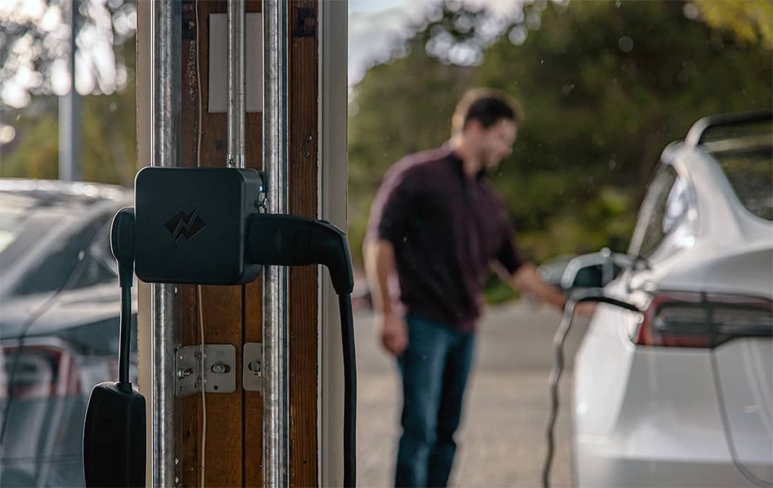 A man charges his car in front of NeoCharge technology.