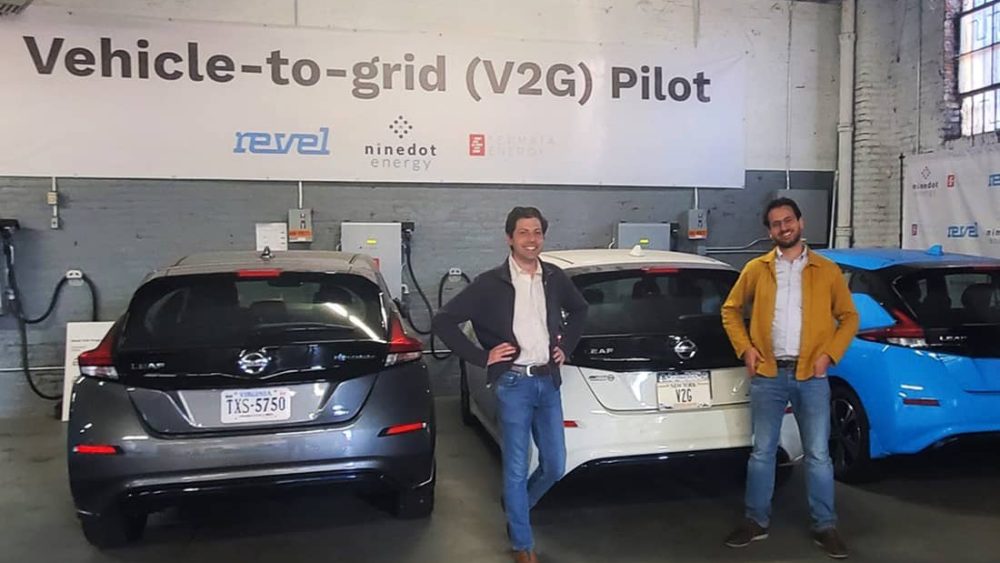 Two men stand in front of 3 vehicles