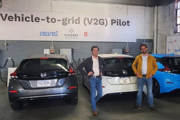 Two men stand in front of 3 vehicles