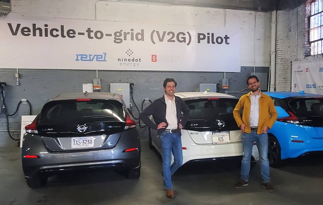 Two men stand in front of 3 vehicles
