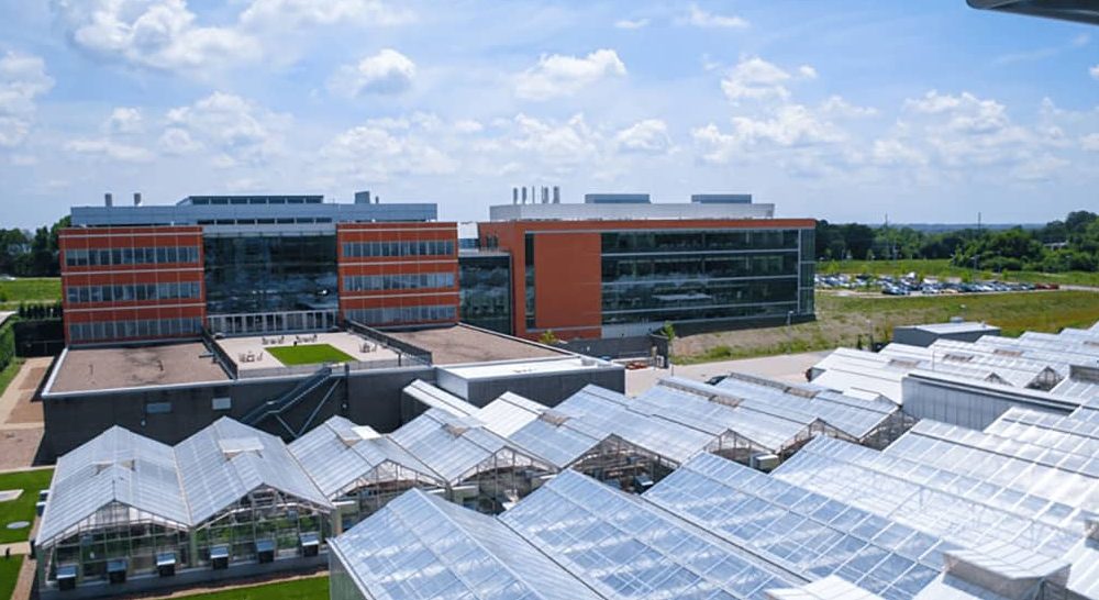 A modern research facility with glass greenhouses in the foreground