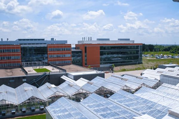 A modern research facility with glass greenhouses in the foreground
