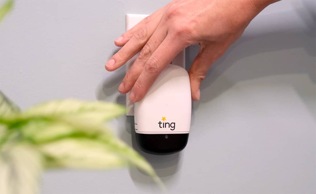Small sensor with the name Ting on it plugged into a wall outlet. A hand is just above it after plugging it in.