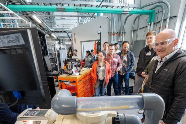 A group of people stand in a lab looking at a machine. Photo courtesy of NREL