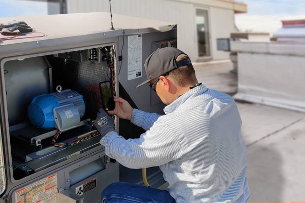 A man installs a piece of machinery on a roof.