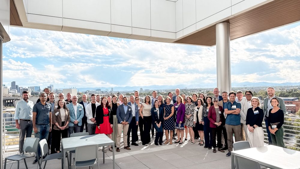 A group of 42 people in professional dress pose for a photo on a building’s rooftop.