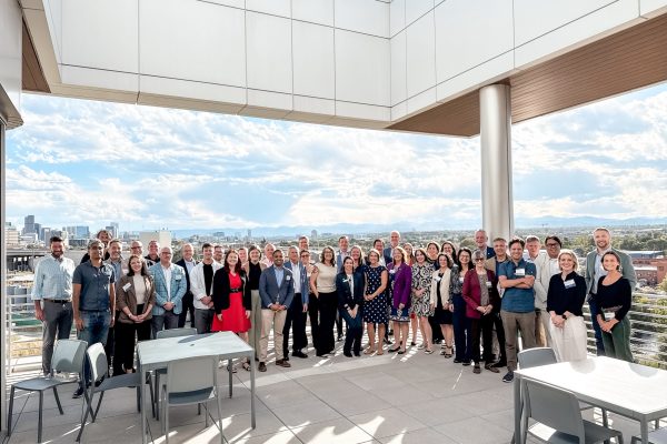 A group of 42 people in professional dress pose for a photo on a building’s rooftop.