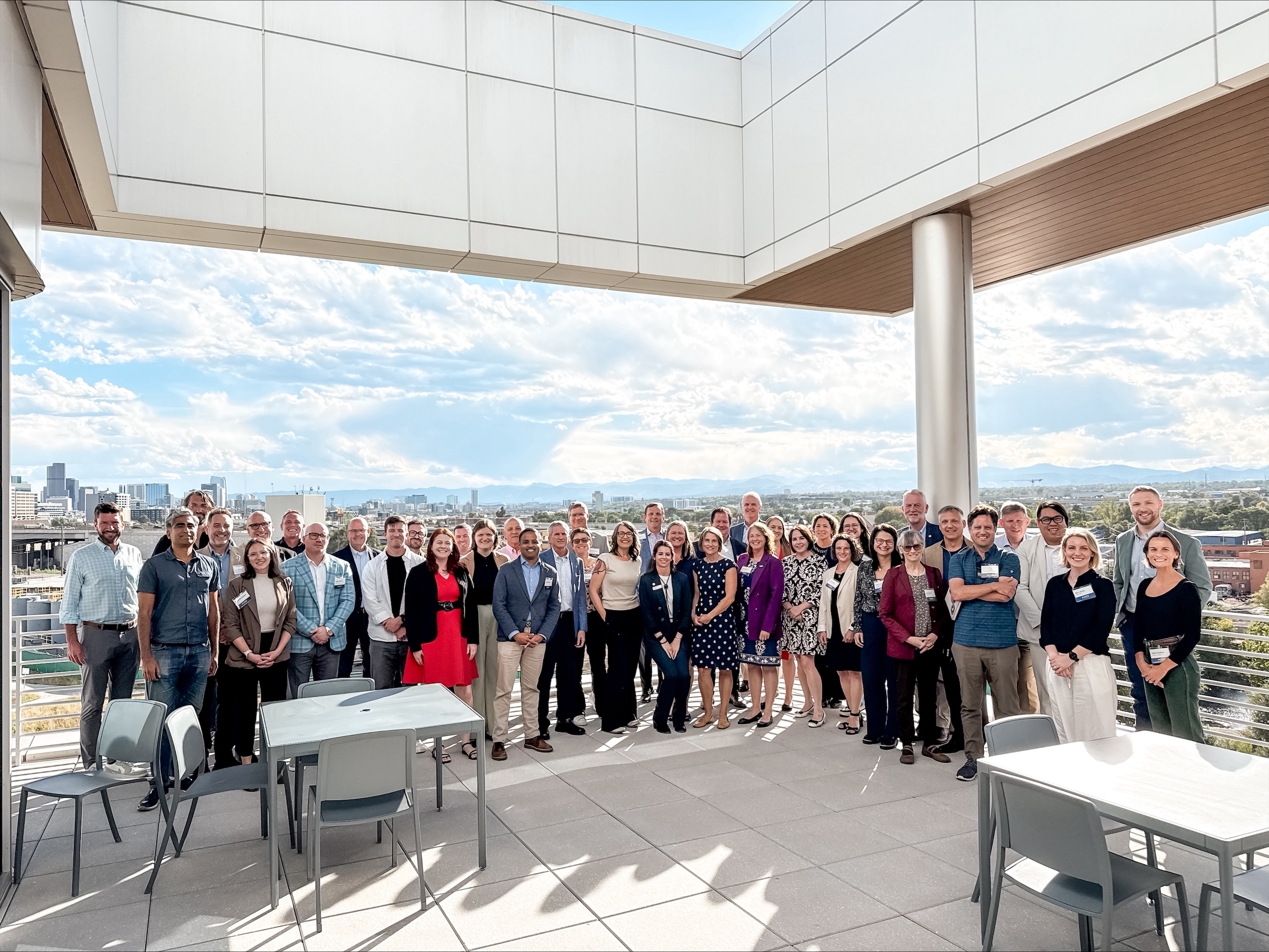 A group of 42 people in professional dress pose for a photo on a building’s rooftop.