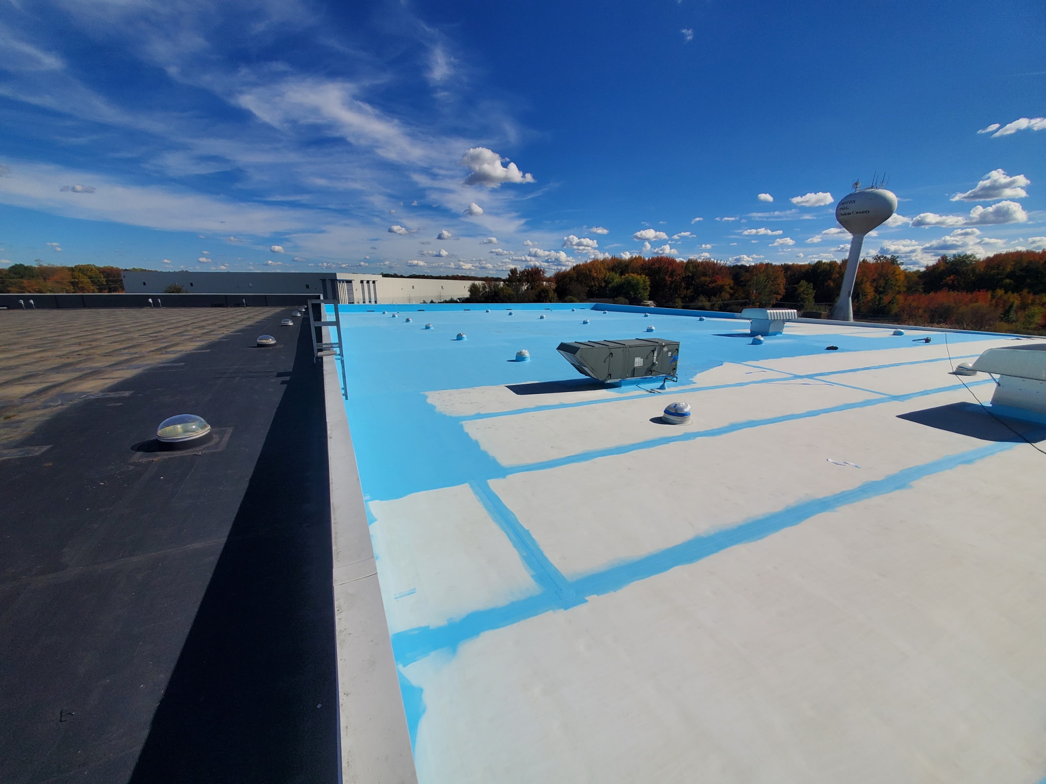 A wide view of a rooftop with a white and blue coating.